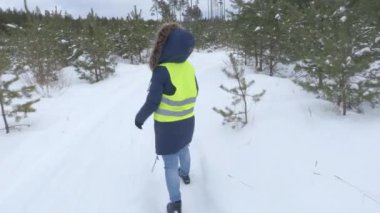 Kışın çam ormanını gösteren kadın