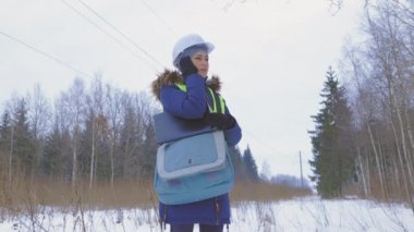 Kadın elektrik mühendisi yüksek voltaj hattının altındaki alanı inceliyor.