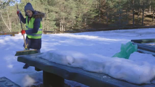 女性ボランティアキャンプ場で雪に覆われたテーブルを削除しようとします — ストック動画
