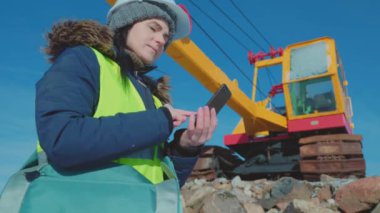 Kazı makinesinin yanında veri yazan kadın mühendis