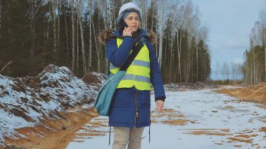 Beyaz şapkalı kadın mimar telefonda konuşuyor.