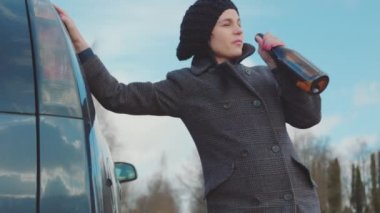  Arabanın yanında alkol kullanan sarhoş kadın.