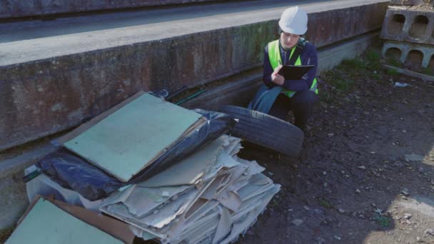 建筑工地上身穿白色安全帽的女工程师在垃圾堆旁写字 — 图库视频影像