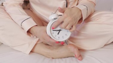 Kadın saat tutuyor ve alarmı kuruyor. Zaman yönetimi kavramı.
