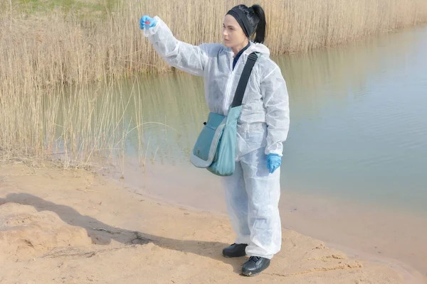 女性生物学家在将试剂添加到瓶子检查水样中后 — 图库照片