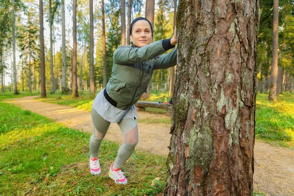 Parktaki Ağacın Yanında Esneme Hareketi Yapan Kadın — Stok fotoğraf