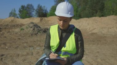 İnşaat alanında inşaat mühendisi kadın notları yazıyor.