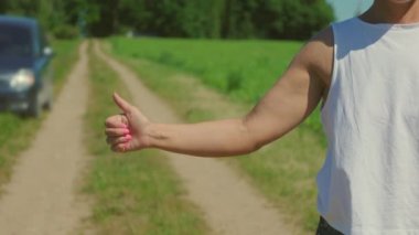 Kırsal yolda arabayı durdurmaya çalışan bir kadın.