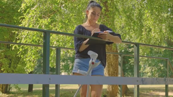 Femme Handicapée Romantique Écrivant Dans Cahier Sur Pont — Video