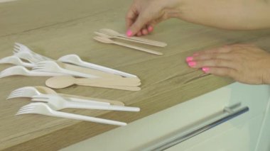 Masada plastik çatalları ve tahta kaşıkları sıralayan kadın.