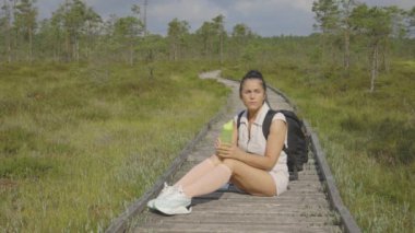 Yürüyüşçü dinleniyor ve bataklıktaki haritaya bakıyor. 