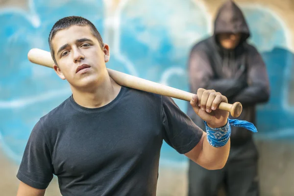 Agressieve tiener met een honkbalknuppel op het opbouwen van achtergrond — Stockfoto