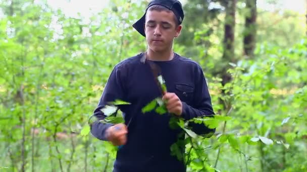 Teen with a knife cuts the branch — Stock Video