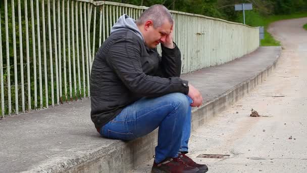 Depressief man zit op de brug — Stockvideo