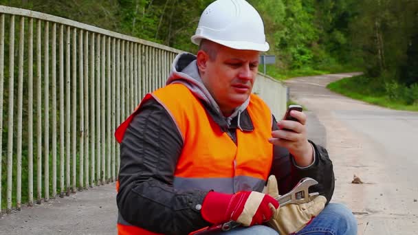 Рабочий с мобильным телефоном на мосту — стоковое видео