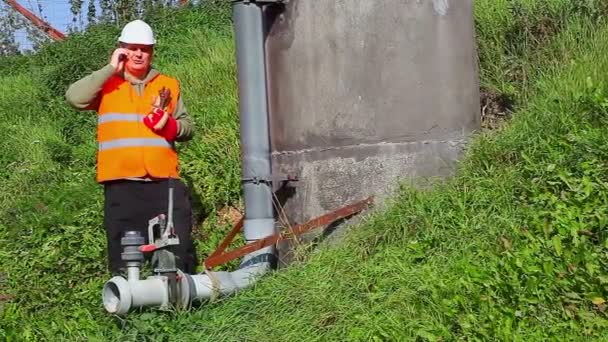 Pracownik z telefonów komórkowych na zewnątrz w pobliżu rur — Wideo stockowe