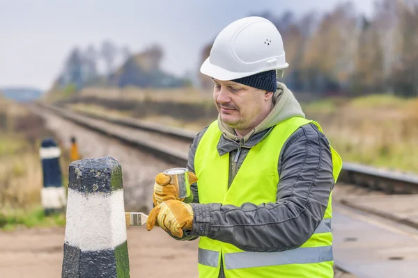 Werknemer met penseel en verf op de spoorwegovergang — Stockfoto