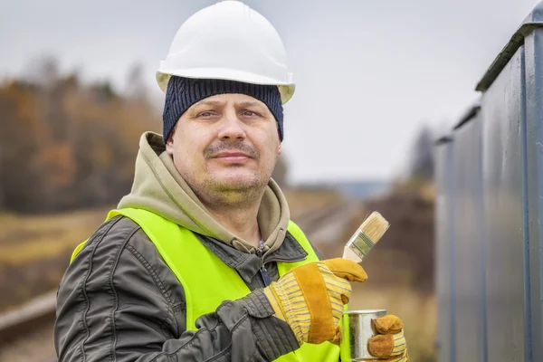 Worker with brush and paint near the railway — Stock Photo, Image