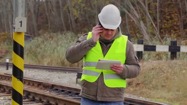 鉄道エンジニアの鉄道の近くの携帯電話で話しています。 — ストック動画