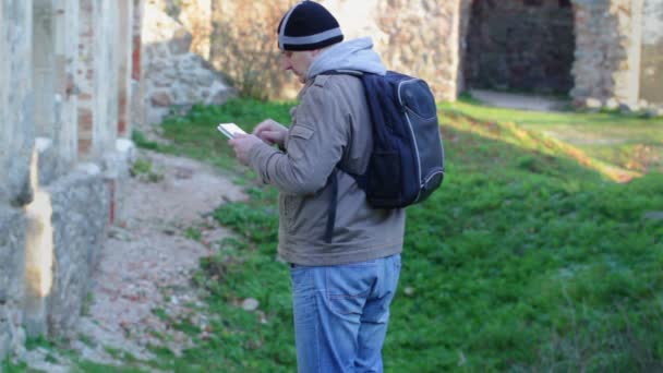 Турист с планшетным компьютером и рюкзаком в руинах — стоковое видео