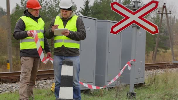 Engenheiro ferroviário com tablet PC e trabalhador com fita de advertência — Vídeo de Stock