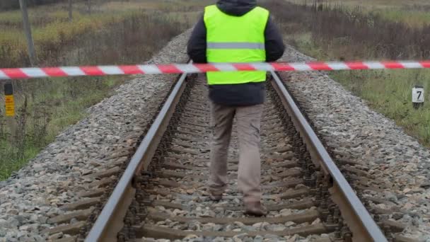 Railway employee behind warning tape on the railway — Stock Video