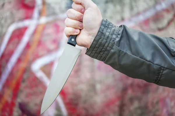 Hand with knife near old wall — Stock Photo, Image