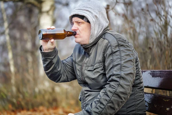 Homme boire de la bière dans la bouteille dans le parc — Photo