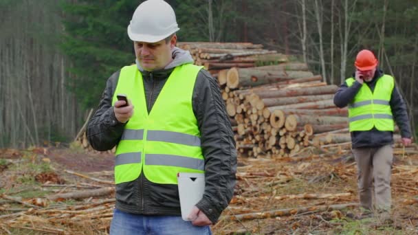Metsävirkailijat puhuvat matkapuhelimissa metsässä — kuvapankkivideo