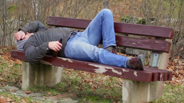 Mann schläft mit Bierflasche auf Bank — Stockvideo