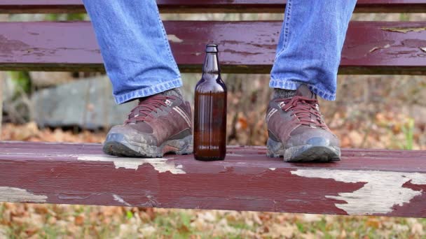 Бутылка пива возле грязных сапог человека — стоковое видео