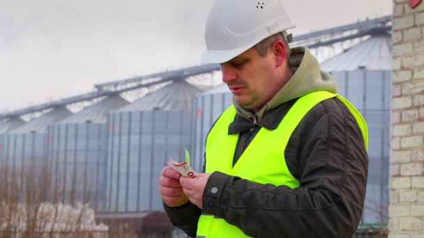 Lavoratore contando i soldi vicino alla fabbrica in inverno — Video Stock