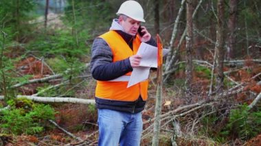 Orman mühendisi ormanda cep telefonuyla konuşuyor.