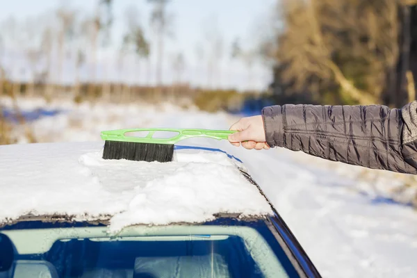 Man reinigt met borstel de auto uit de sneeuw — Stockfoto