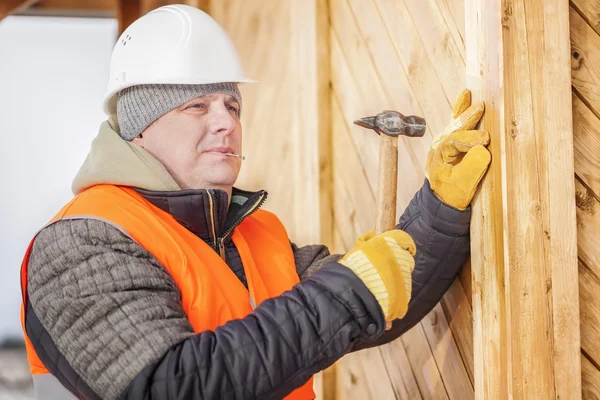 Carpenter drives a nail in board — Stock Photo, Image