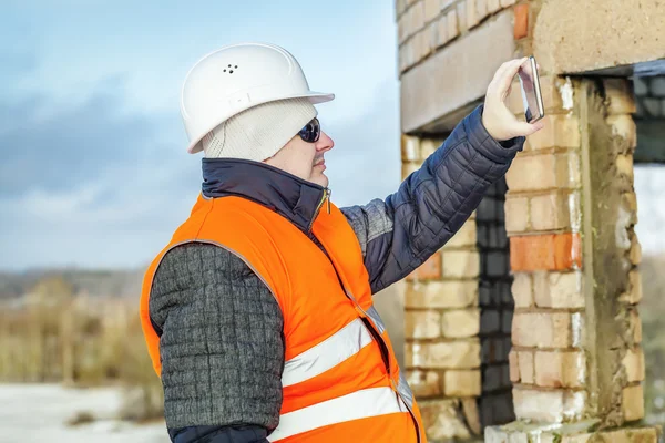 Engenheiro com tablet PC tirar uma foto perto de edifício inacabado — Fotografia de Stock