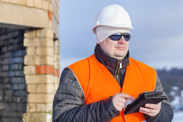 Worker with tablet PC near unfinished building — Stock Photo, Image