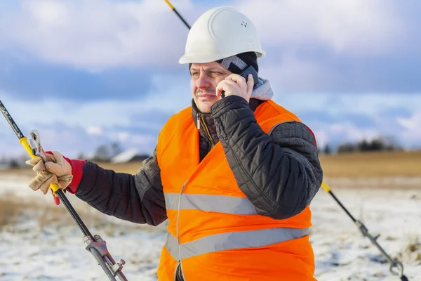 Engenheiro elétrico falando no telefone celular perto do tensionador Fotografia De Stock