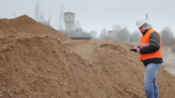 Civil engineer with tablet PC at a pile of sand — Stock Video