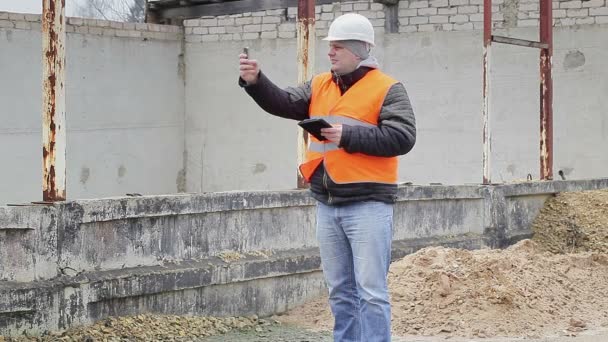 Engenheiro civil com telefone celular perto do prédio inacabado — Vídeo de Stock