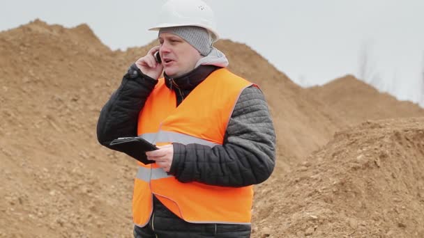 Stavební inženýr mluvil na mobil v hromadu písku — Stock video