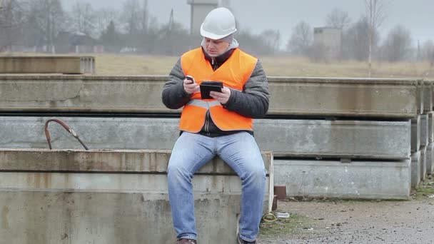 Инженер с мобильным телефоном и планшетным ПК на бетонных панелях — стоковое видео