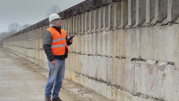 Ingenieur mit Tablet-PC läuft nahe der Betonwand — Stockvideo