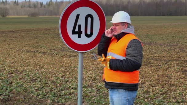 Arbetaren talar i mobiltelefon nära Vägmärke — Stockvideo