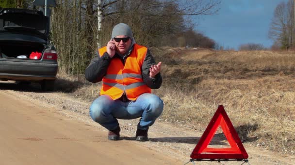 Man talar i mobiltelefon nära varningstriangel — Stockvideo