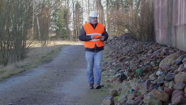 Pracownik z tabliczka Pc na drogi w pobliżu hotelu stosy kamieni — Wideo stockowe