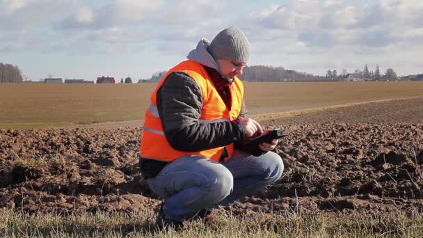 Boer met tablet Pc in de buurt van geploegd veld in het vroege voorjaar — Stockvideo