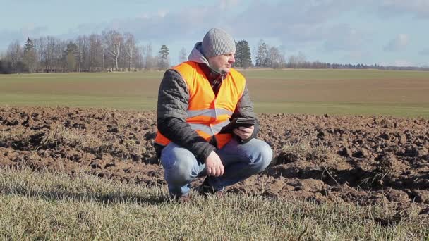 Boer met tablet Pc in de buurt van geploegd veld — Stockvideo