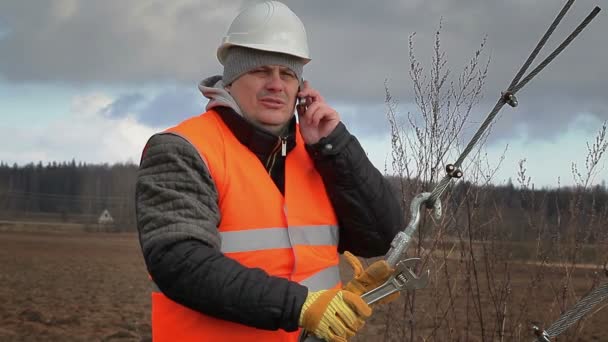 Werknemer met mobiele telefoon en verstelbare sleutel op veld — Stockvideo