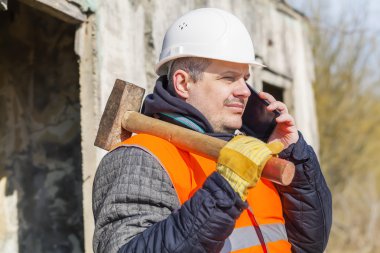 İşçi cep telefonuyla konuşurken kızak çekiç ile